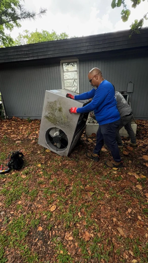 Florida Power Comfort technicians carrying a condenser unit for installation