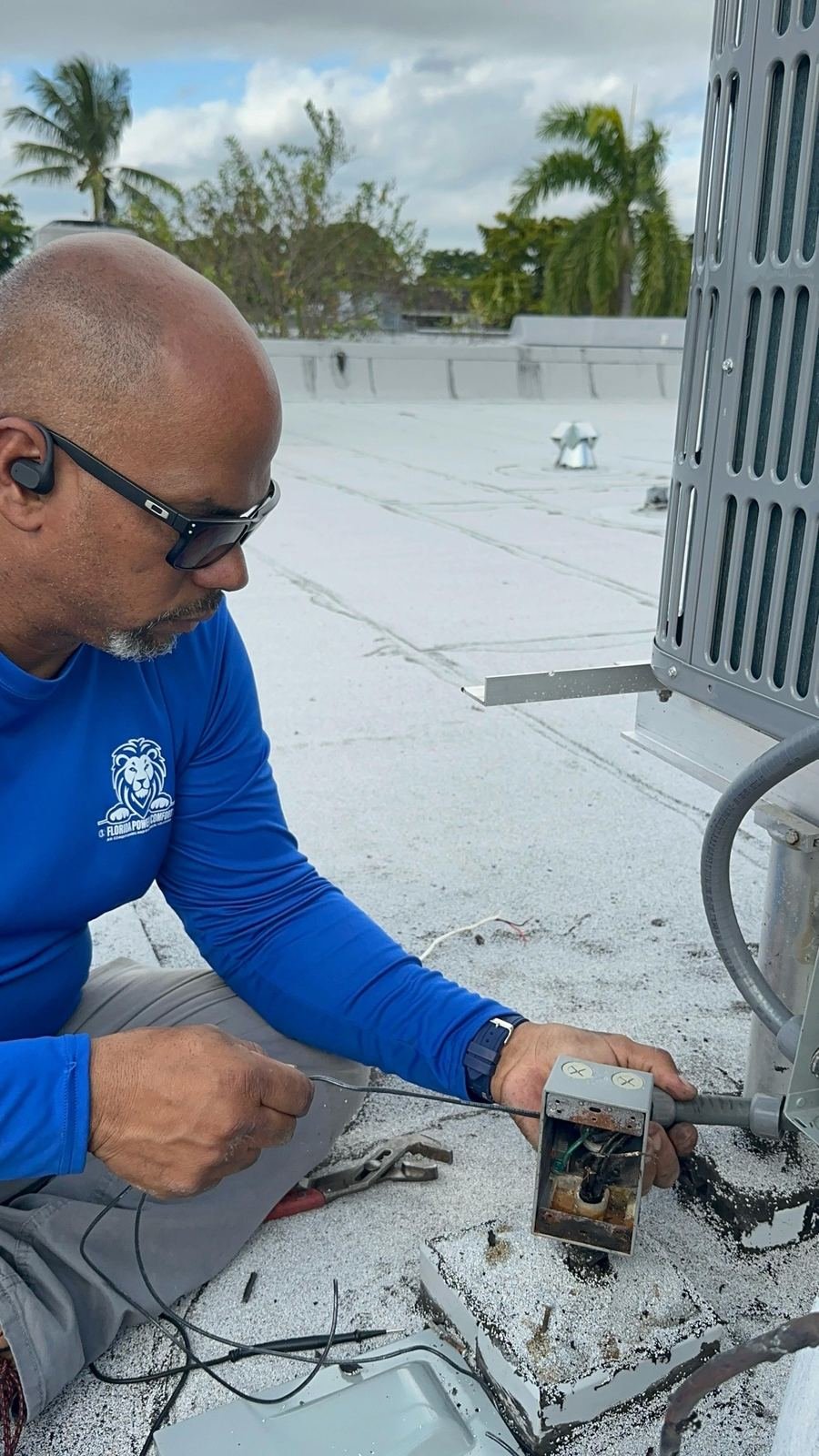 Technician troubleshooting a rooftop AC electrical junction box