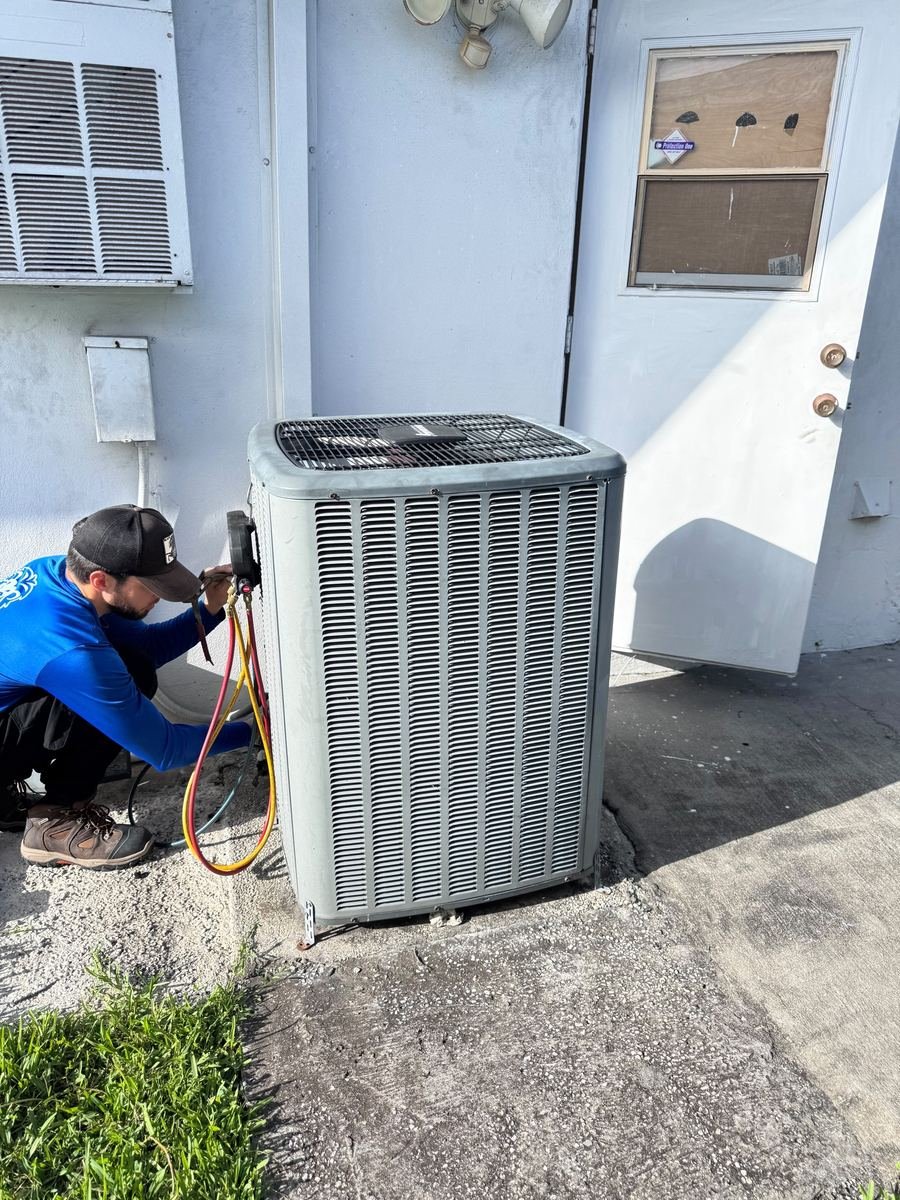Technician connecting gauges to a new AC condenser unit