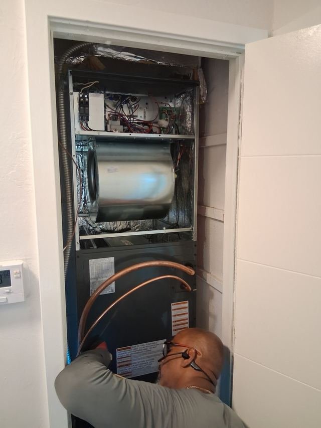 Technician servicing an air handler in a closet