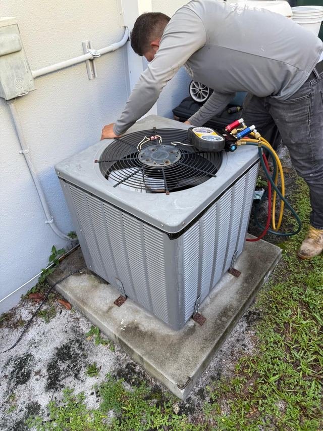 Technician checking refrigerant pressures on a condenser