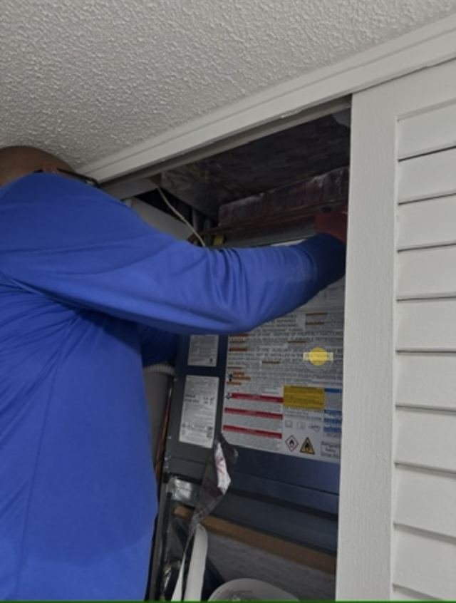 Technician accessing attic HVAC system