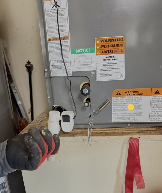 Technician servicing air handler drain fitting