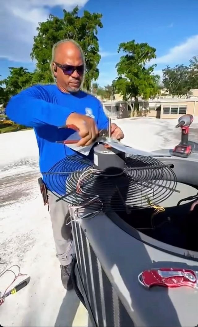 Technician servicing a rooftop condenser fan motor