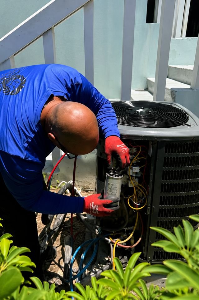 Technician replacing an AC capacitor on an outdoor condenser