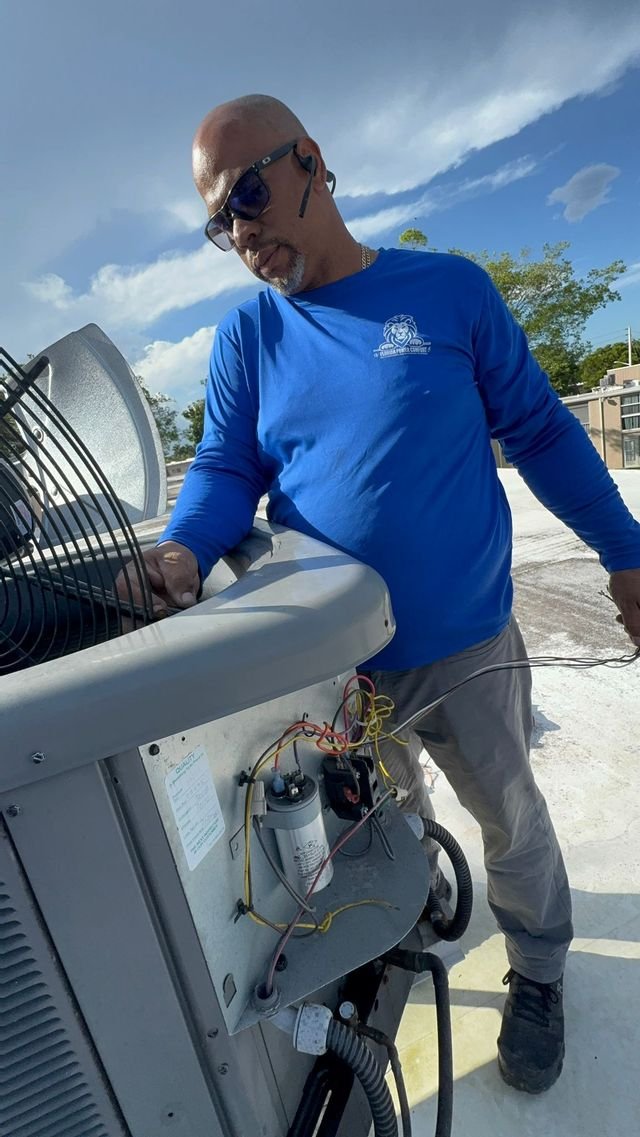 Technician servicing a rooftop condenser capacitor