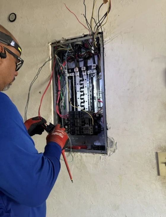 Technician working inside an open electrical panel