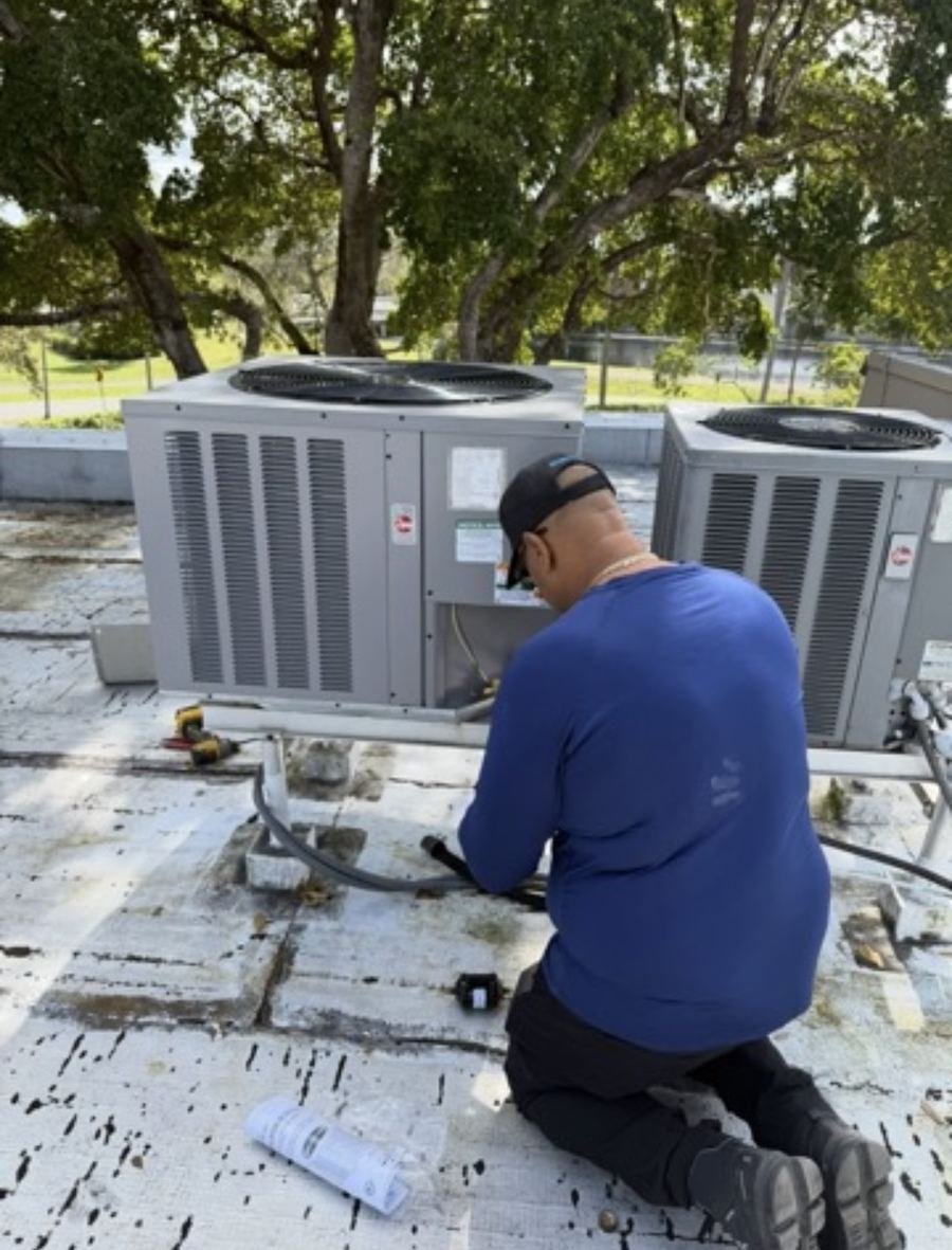 Technician installing a rooftop commercial AC condenser unit