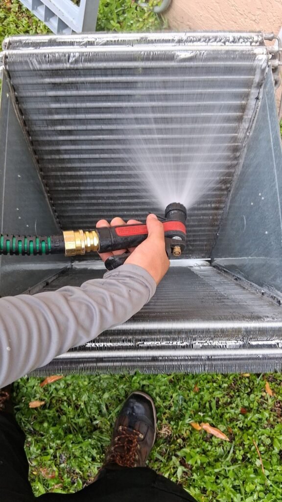 Technician rinsing an AC coil during a tune-up
